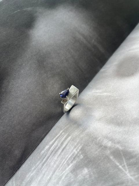 Silver ring with a blue gemstone on a textured surface