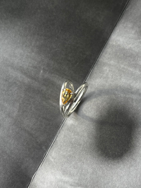 Silver ring with a yellow gemstone on a gray surface