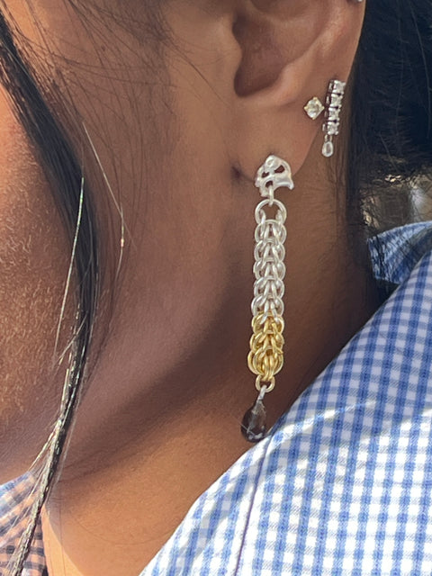 Close-up of a person wearing a silver and gold bracelet on their ear.