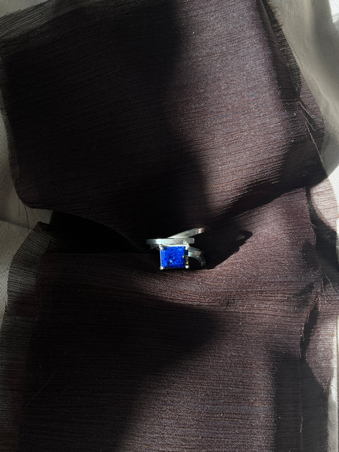 Ring with a blue gemstone on a dark fabric background